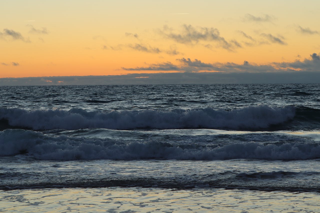 Vibrant sunset over Lège-Cap-Ferret seascape with waves crashing on the shore.